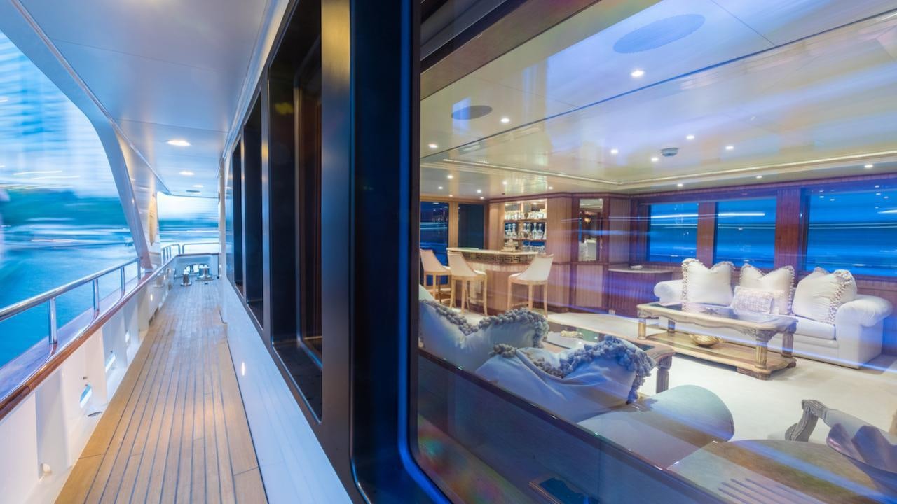 a room with a wood deck and a large window with a view of the city aboard BARENTS Yacht for Charter