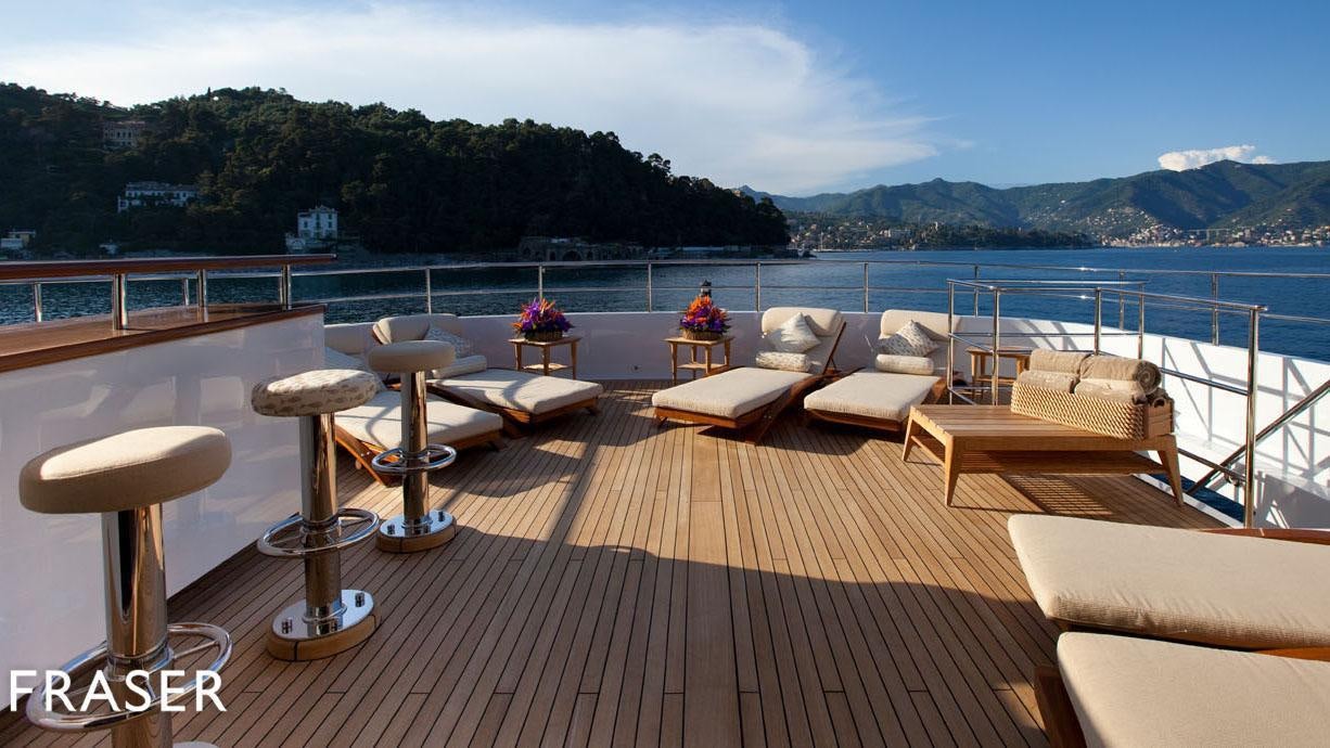 a deck with chairs and tables on it by a body of water aboard ELENA V Yacht for Charter