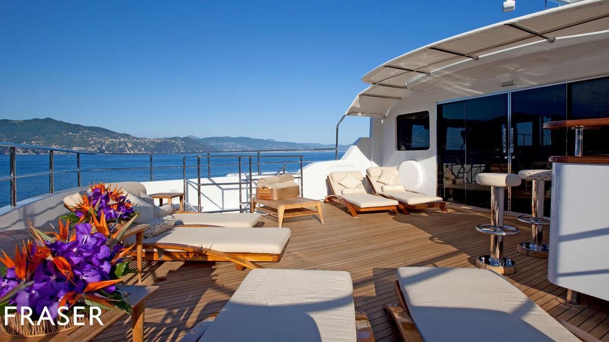 a deck with a view of the ocean and a large boat aboard ELENA V Yacht for Charter