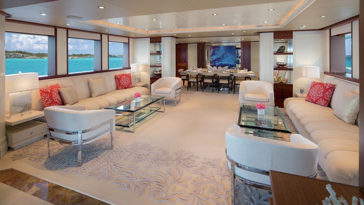a living room with a large white rug and a large window aboard PISCES Yacht for Charter