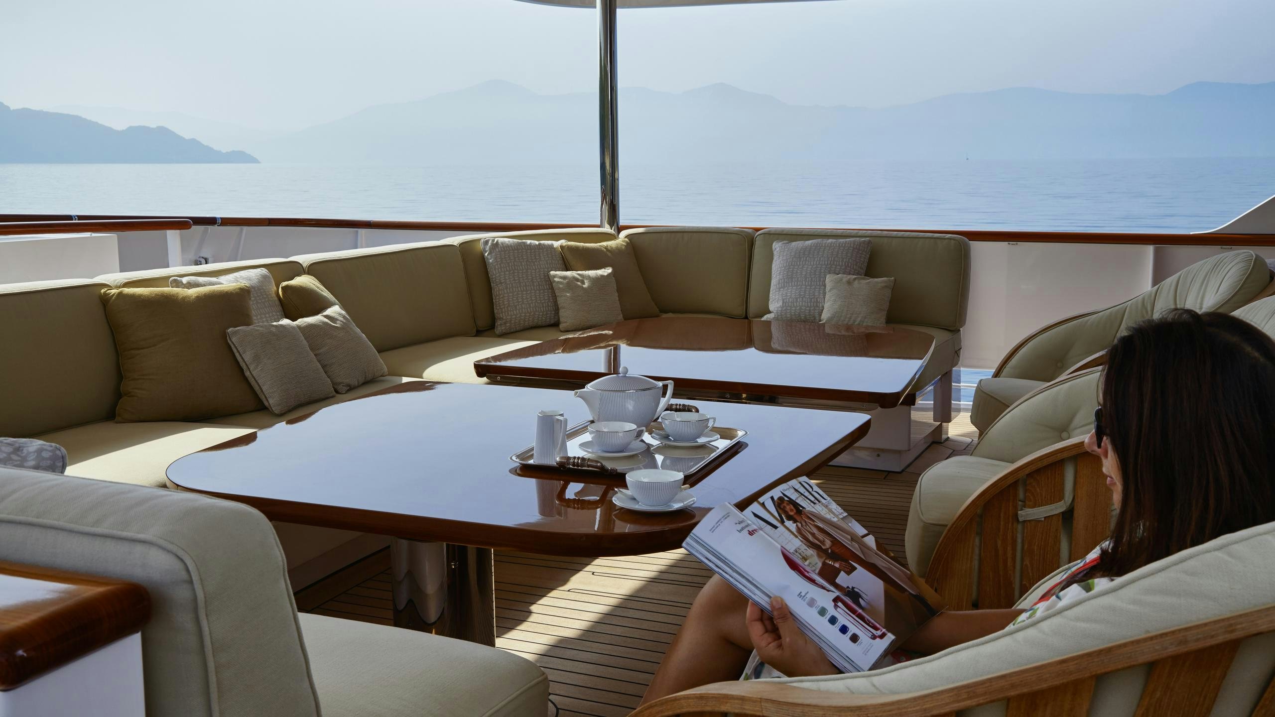 a person reading a book on a couch aboard ANCALLIA Yacht for Charter