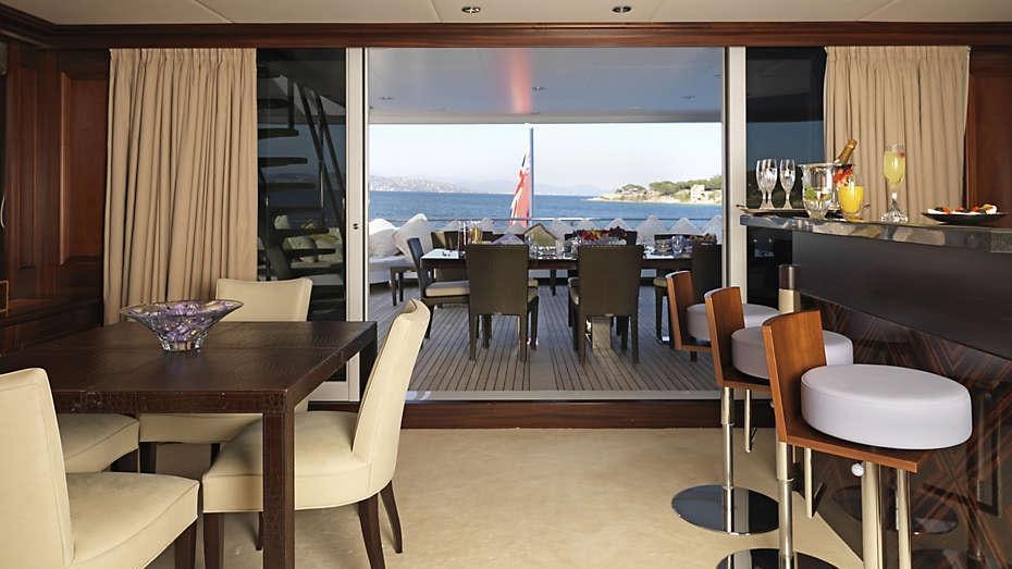 a room with a table chairs and a window with a view of the water aboard MY LITTLE VIOLET Yacht for Charter