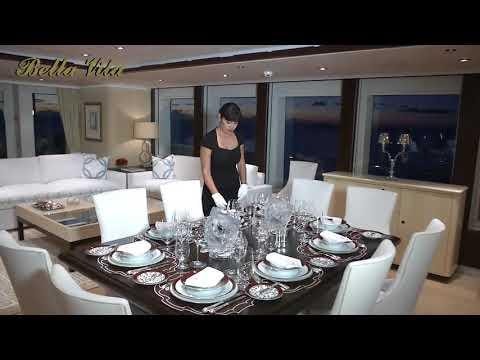 a person standing next to a table with plates and glasses on it aboard BELLA Yacht for Charter