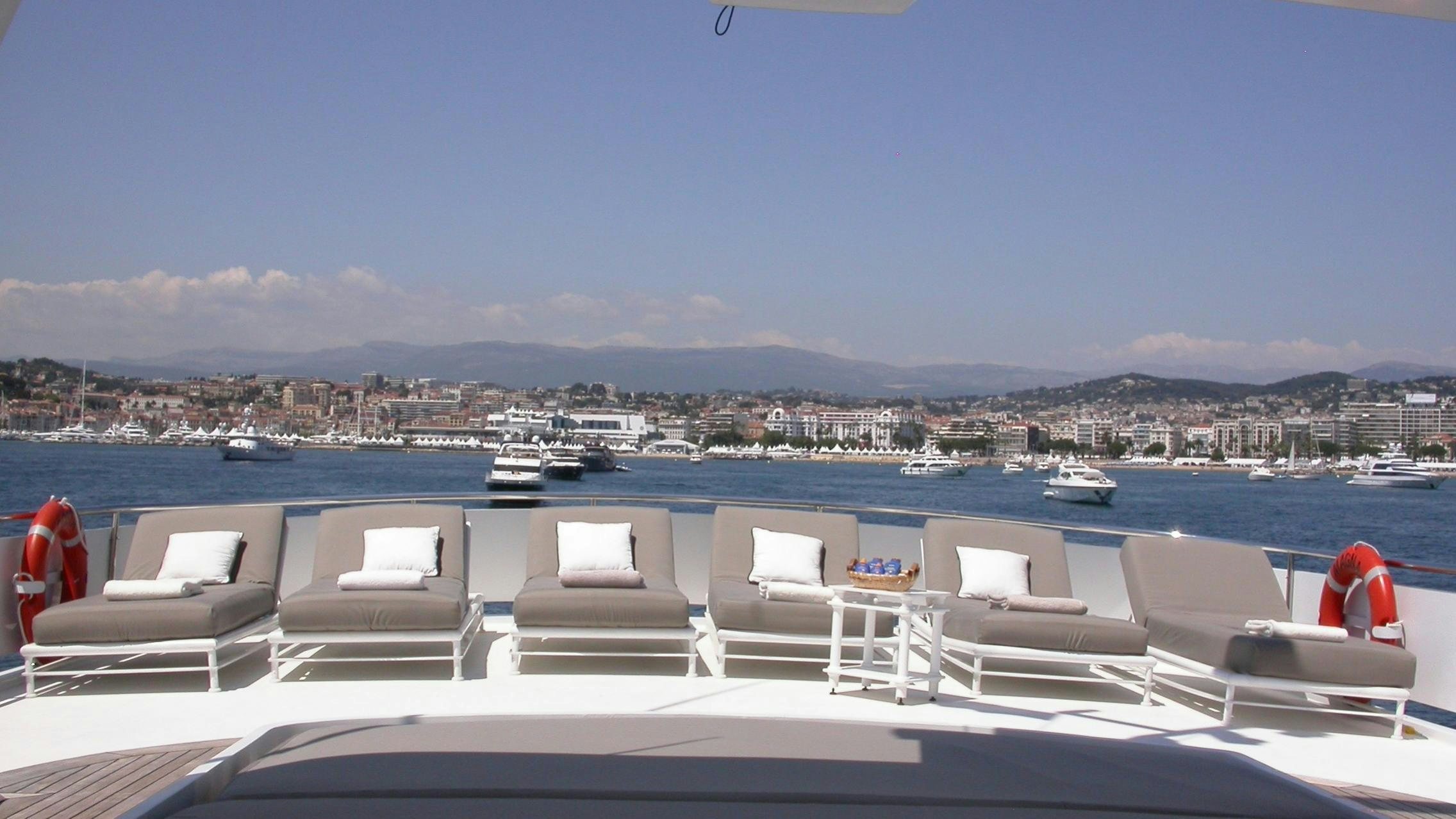 a boat dock with lounge chairs and boats on it aboard COSTA MAGNA Yacht for Charter