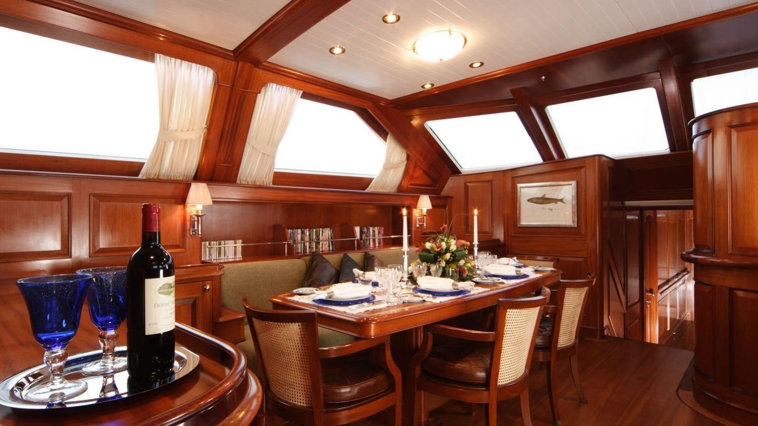 a dining table and chairs in a room with a window aboard CAVALLO Yacht for Charter