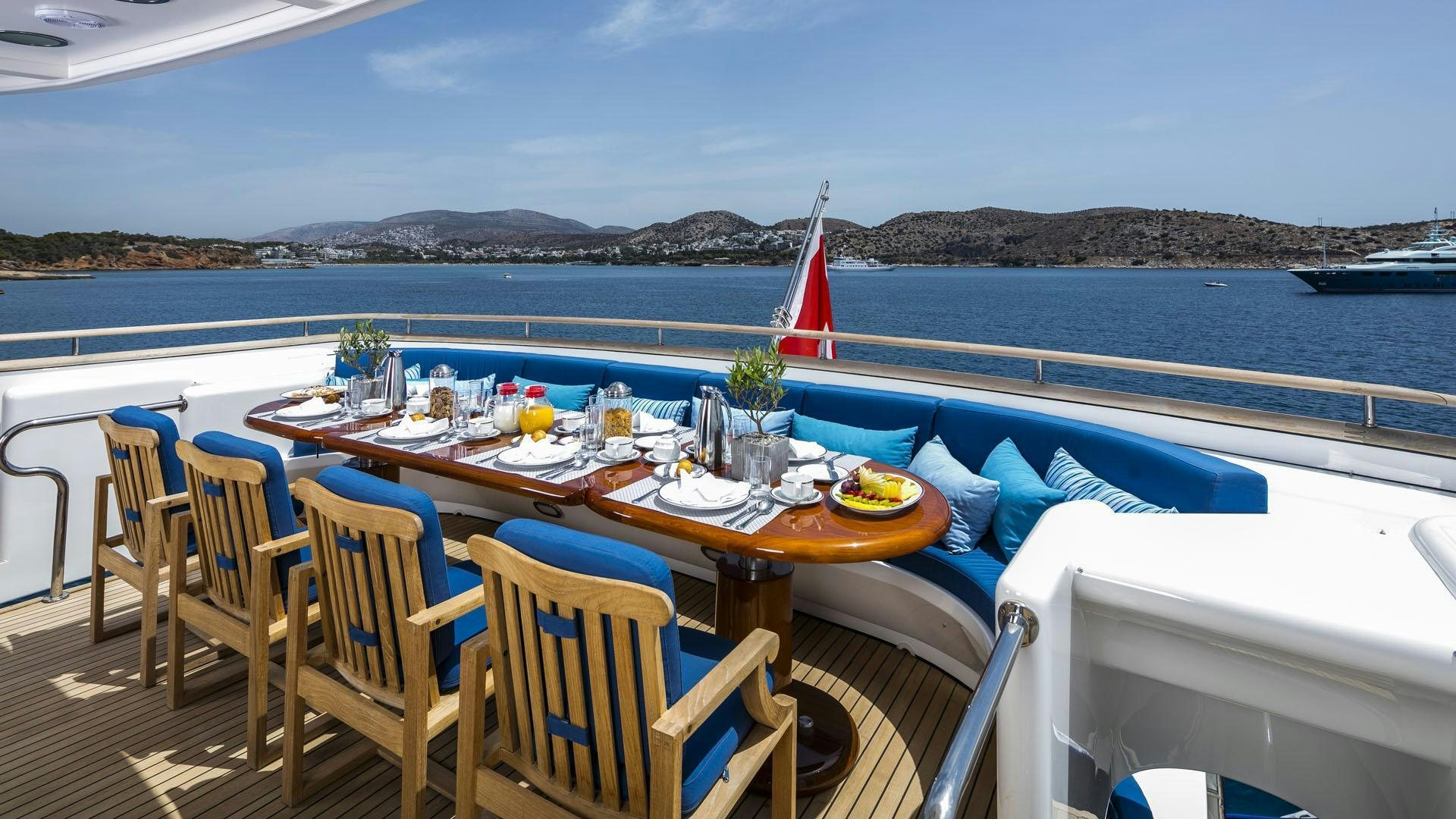 a table set for a meal on a deck overlooking a body of water aboard JAAN Yacht for Charter