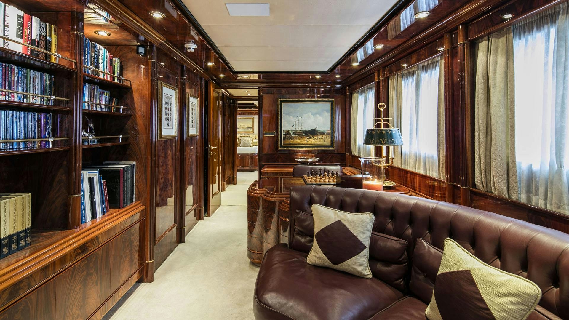 a living room with a brown leather couch and a bookcase aboard JAAN Yacht for Charter