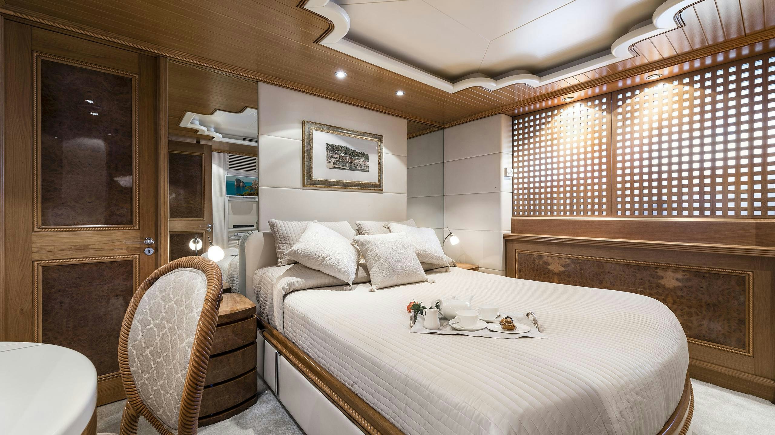 a large bedroom with a bed and a chair aboard DESAMIS B Yacht for Charter