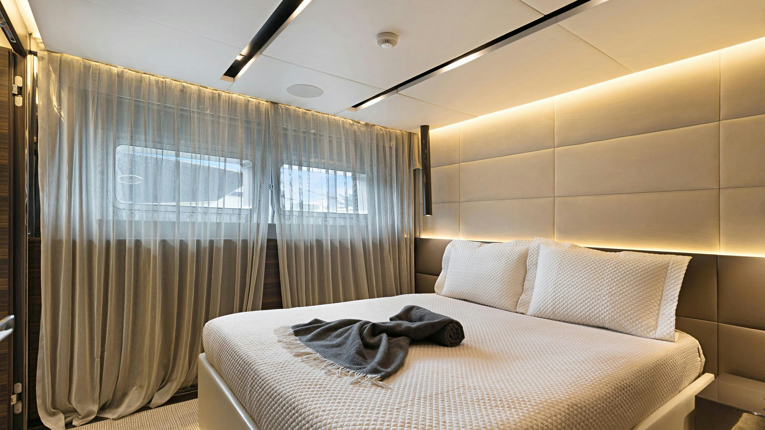 a bed with a white sheet and a blue curtain aboard SAFE HAVEN Yacht for Charter