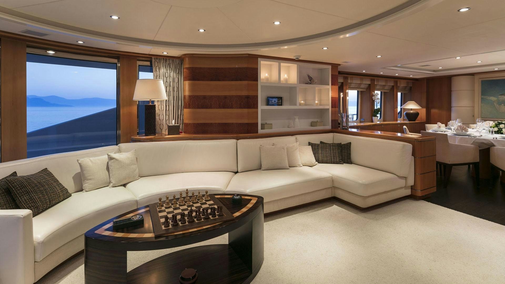 a living room with a large white couch and a large window aboard L'EQUINOX Yacht for Charter