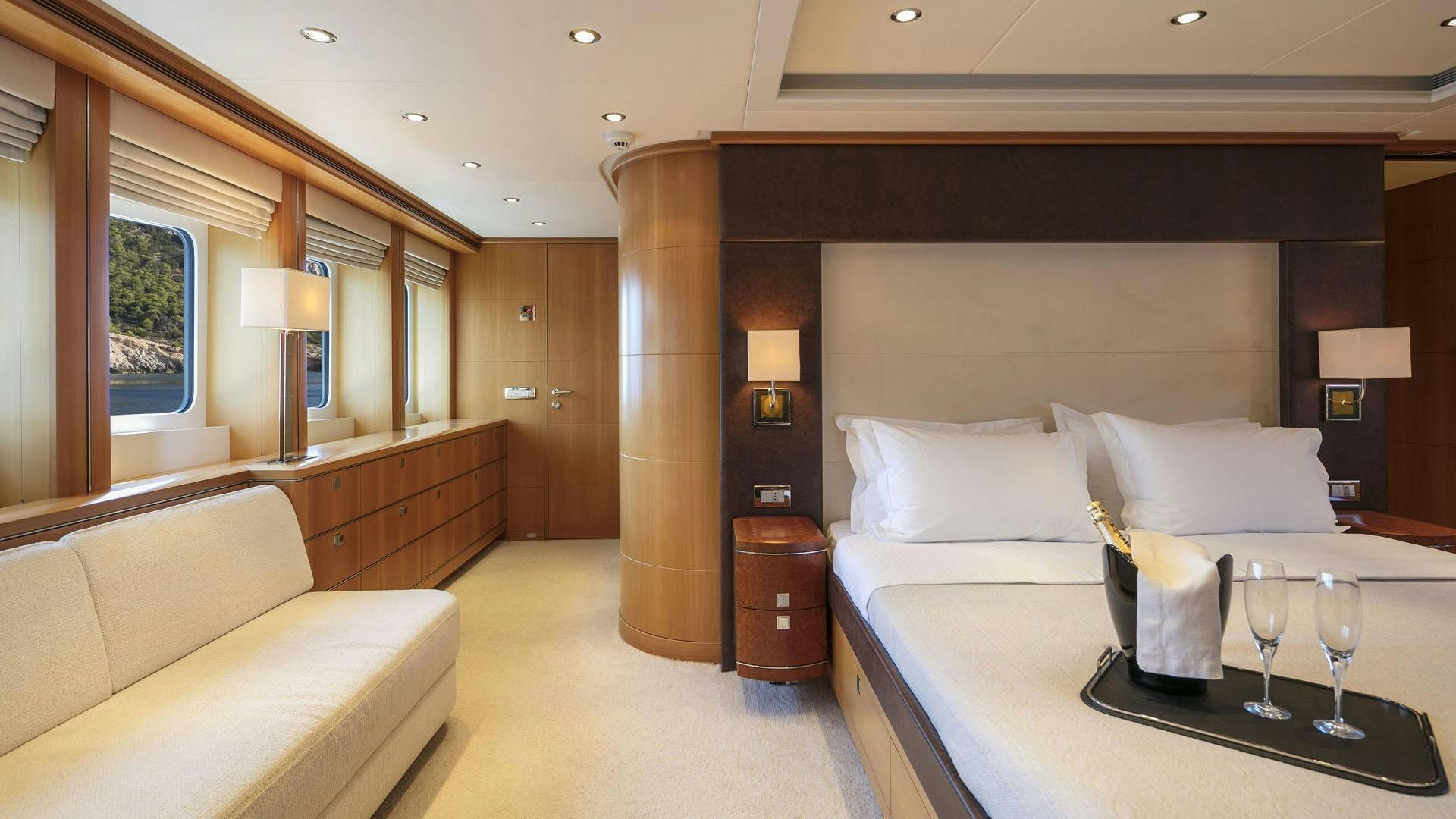 a hotel room with a bed and wine glasses aboard L'EQUINOX Yacht for Charter