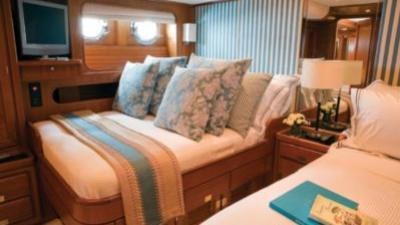 a bed with a pillow and a television on the wall aboard GITANA Yacht for Charter