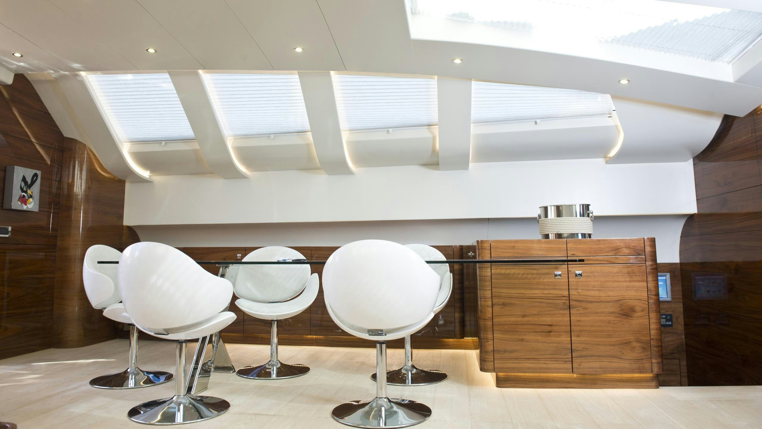 a group of white chairs in a room with a wood cabinet and a white ceiling aboard MUSIC Yacht for Charter
