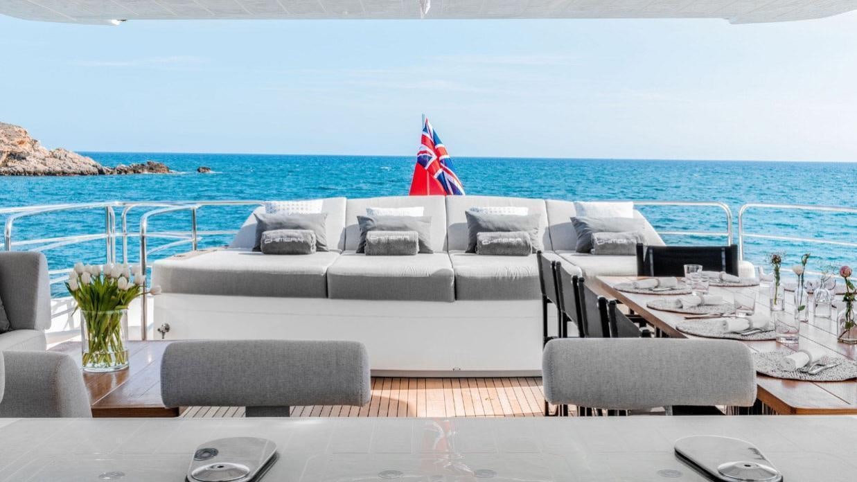 a large white couch with a red umbrella on it next to a large body of water aboard OKSANCHIK Yacht for Charter