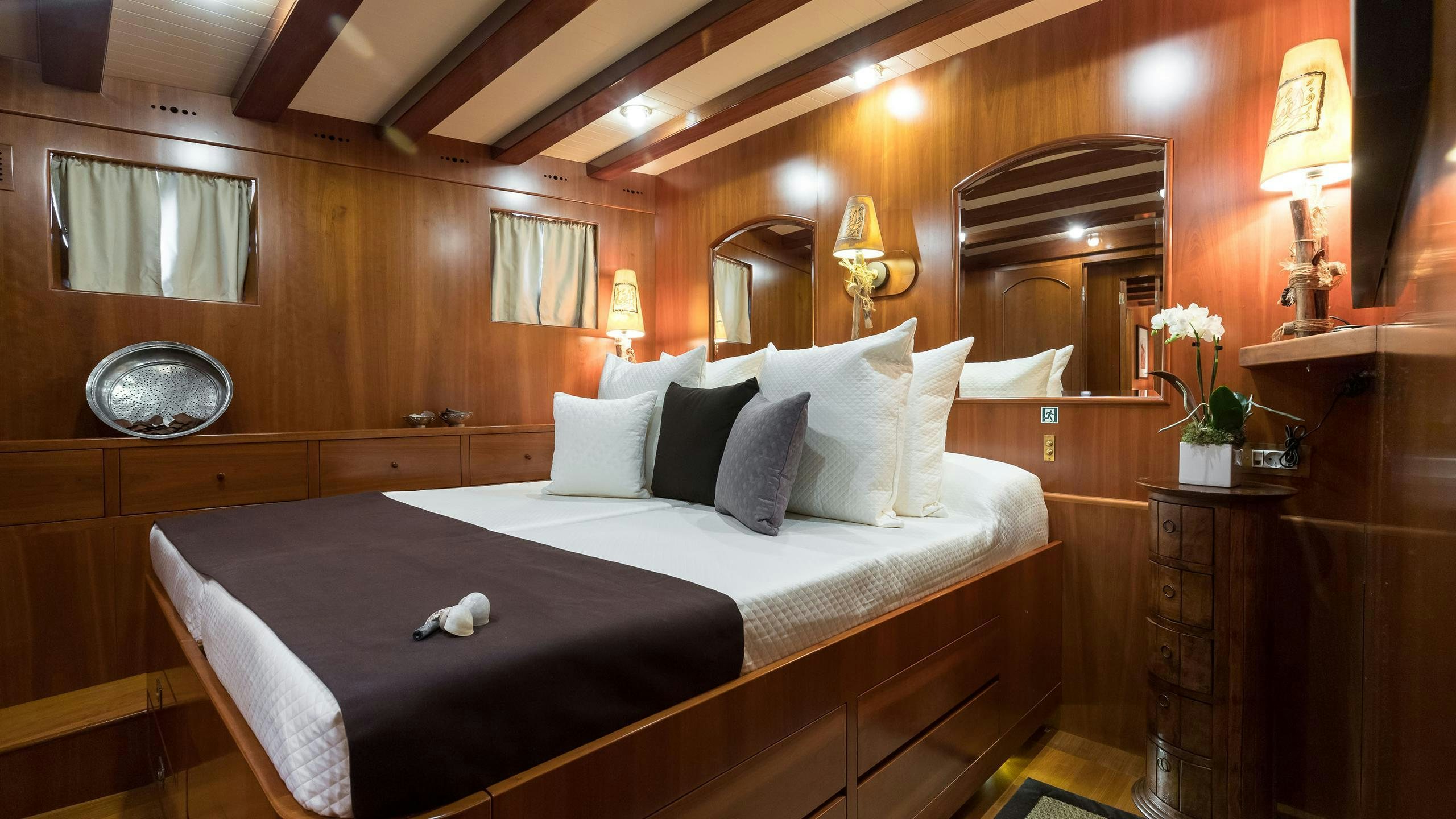 a bed with a white sheet and pillows in a room with wood walls aboard OVER THE RAINBOW OF LONDON Yacht for Charter