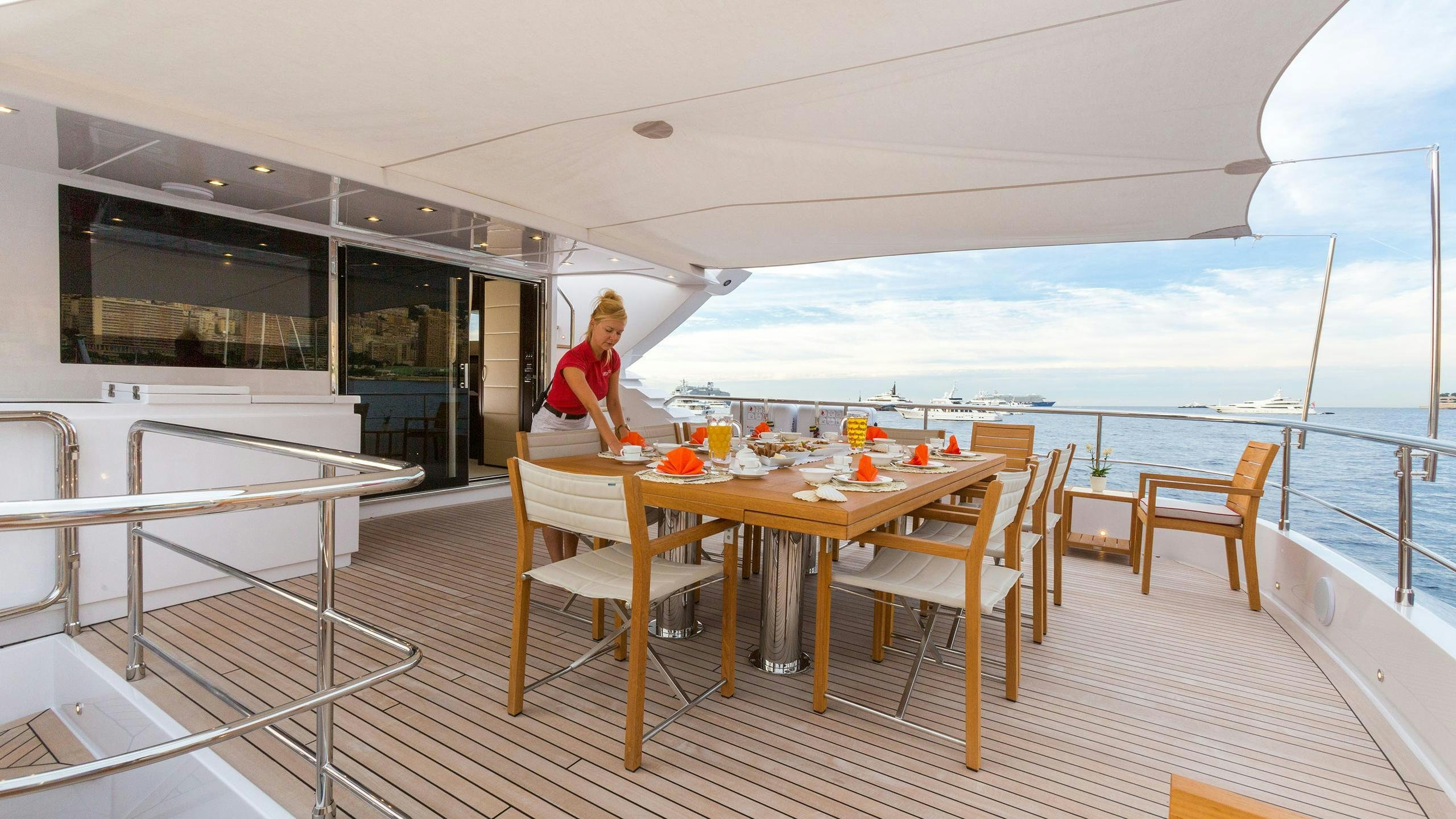 a person standing at a table on a deck overlooking the ocean aboard GATSBY Yacht for Charter