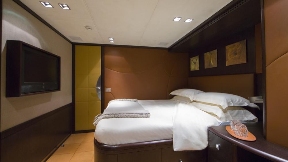 a hotel room with a bed and tv aboard QUID PRO QUO Yacht for Charter