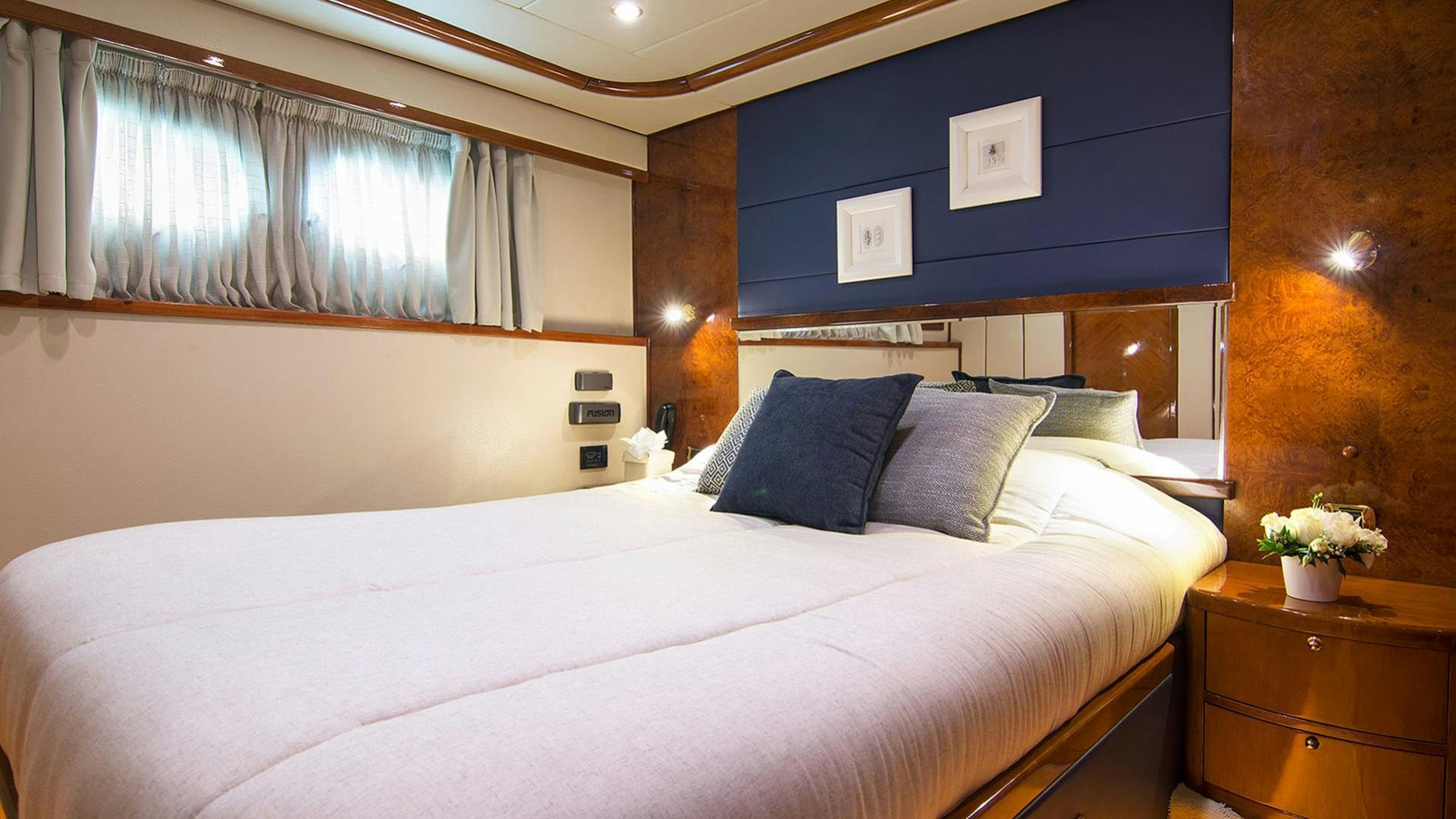a bed with a white sheet and pillows in a room with a window aboard DREAM B Yacht for Charter