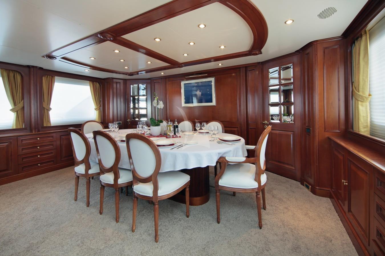 a dining table and chairs in a room with wood cabinets aboard INOUIS Yacht for Charter