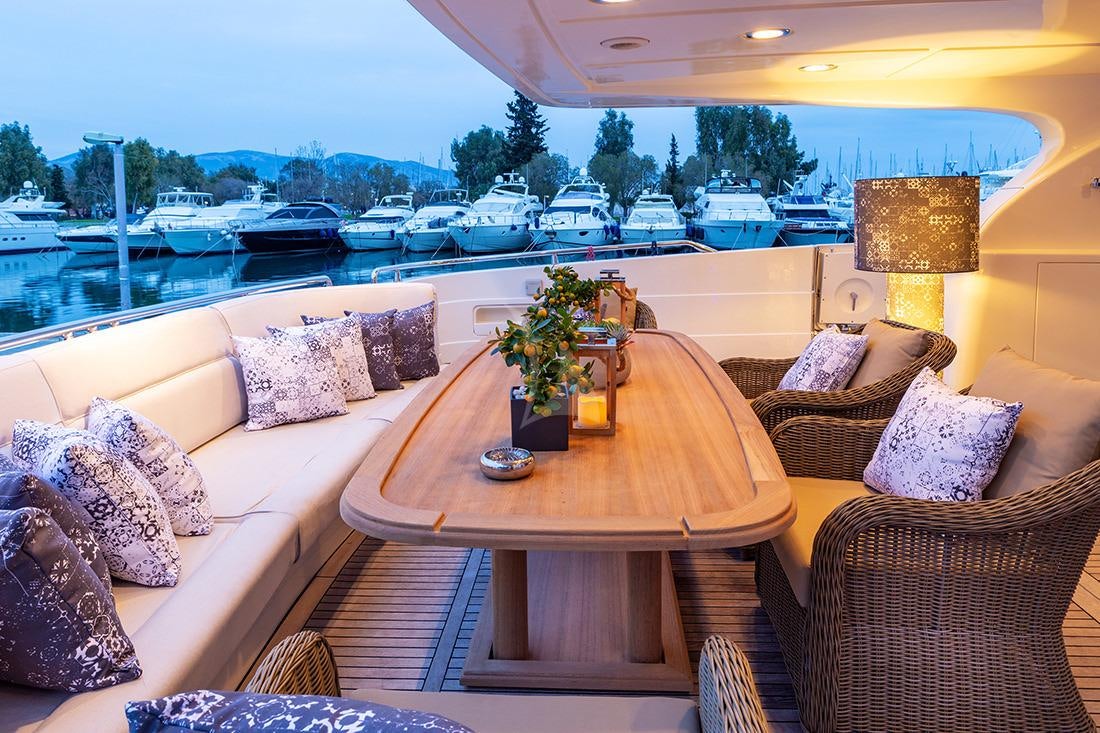 a table with chairs and a couch on a deck overlooking a body of water aboard DIVINE Yacht for Charter