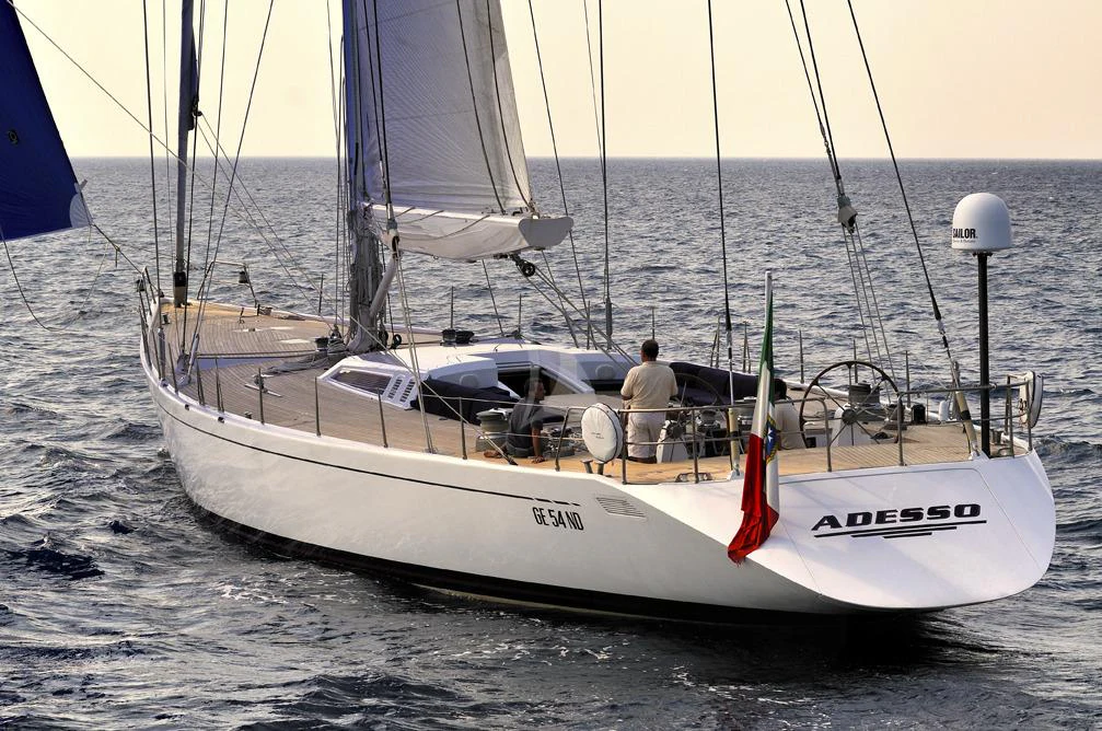 a white boat with a red and black sail on the water aboard ADESSO Yacht for Charter