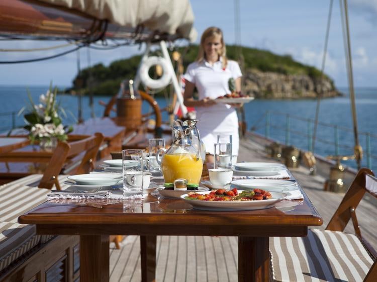 a person standing at a table with food on it aboard ELENA OF LONDON Yacht for Charter