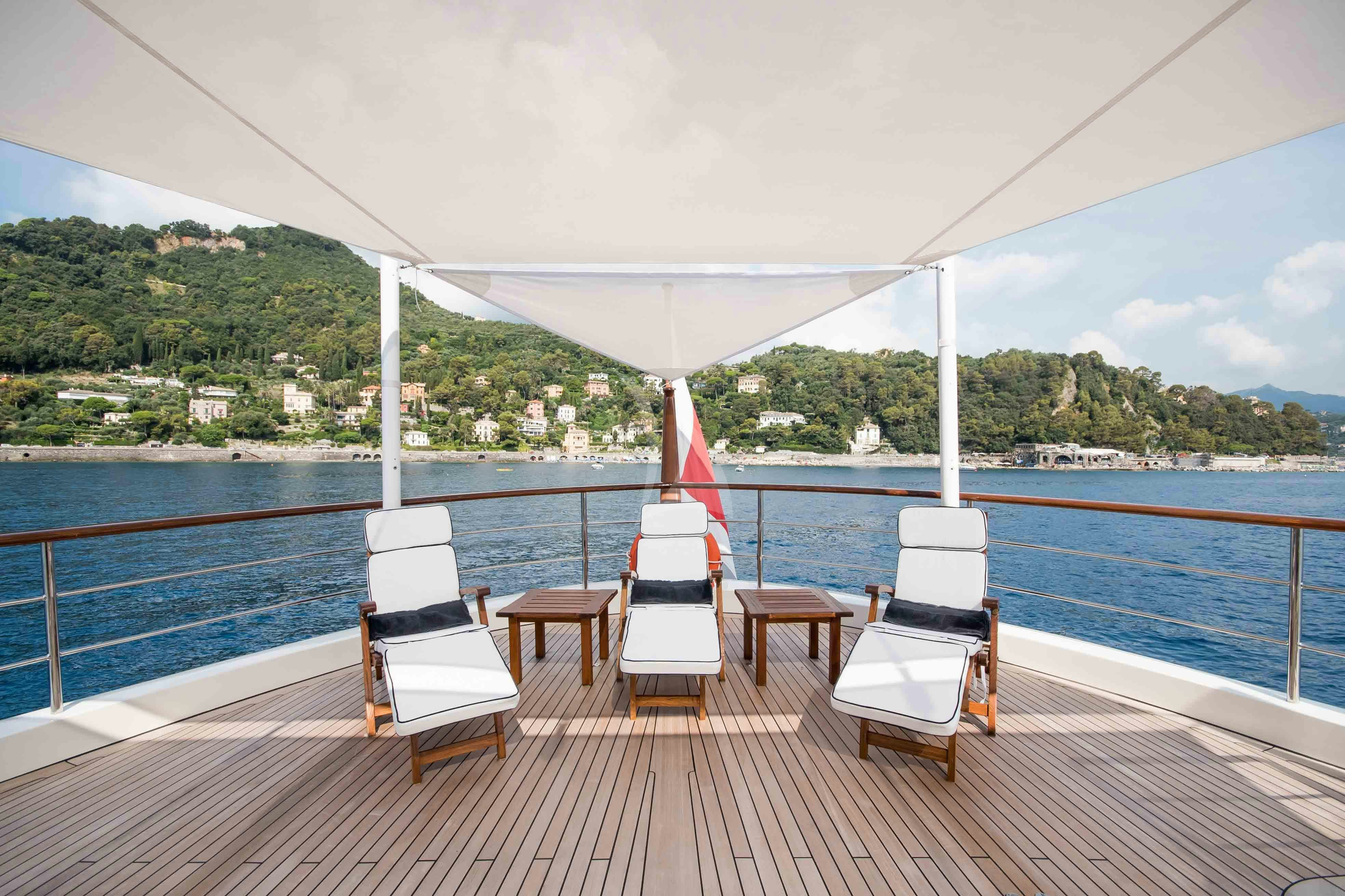 a deck with chairs and tables on it by a body of water aboard ELENI Yacht for Charter