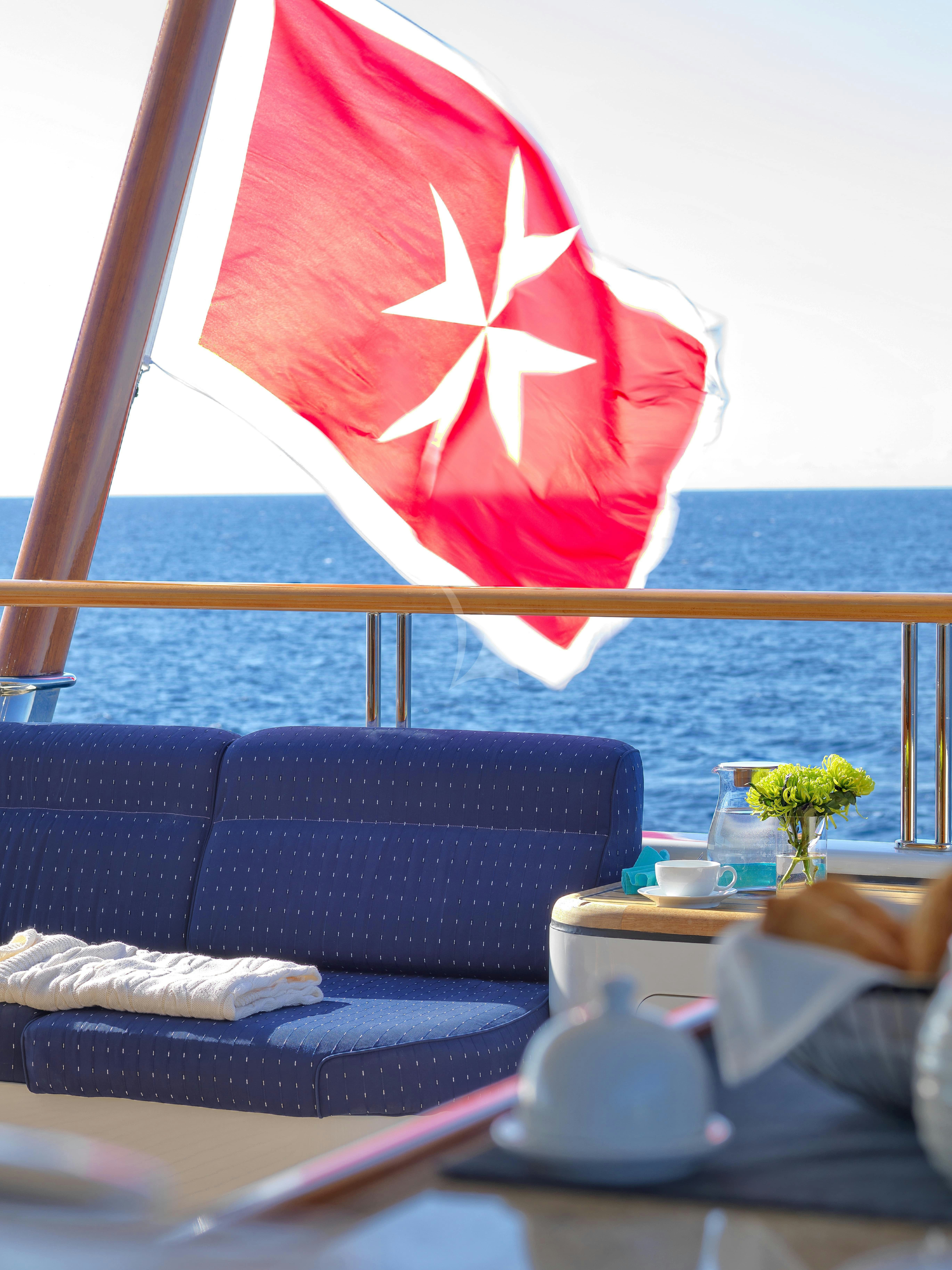 a red and white flag over a blue couch aboard CAPRI I Yacht for Charter