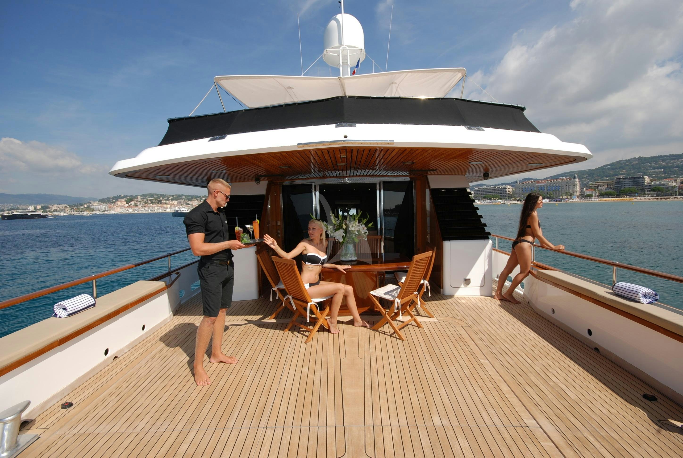 a man standing on a deck of a boat with a woman sitting on it aboard ATLANTIC ENDEAVOUR Yacht for Charter