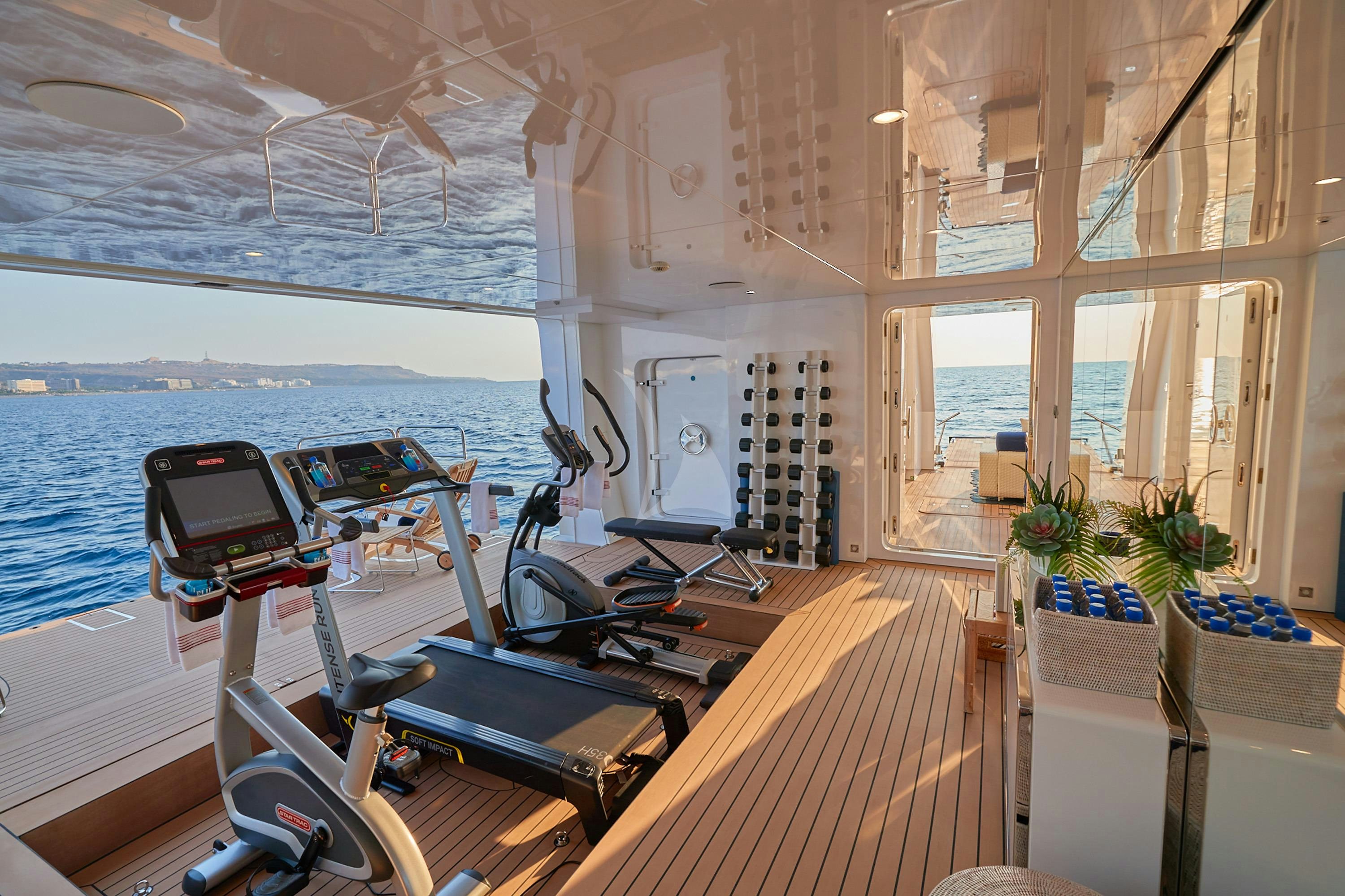 a boat with a deck and a table with chairs and a large window aboard ALMAX Yacht for Charter