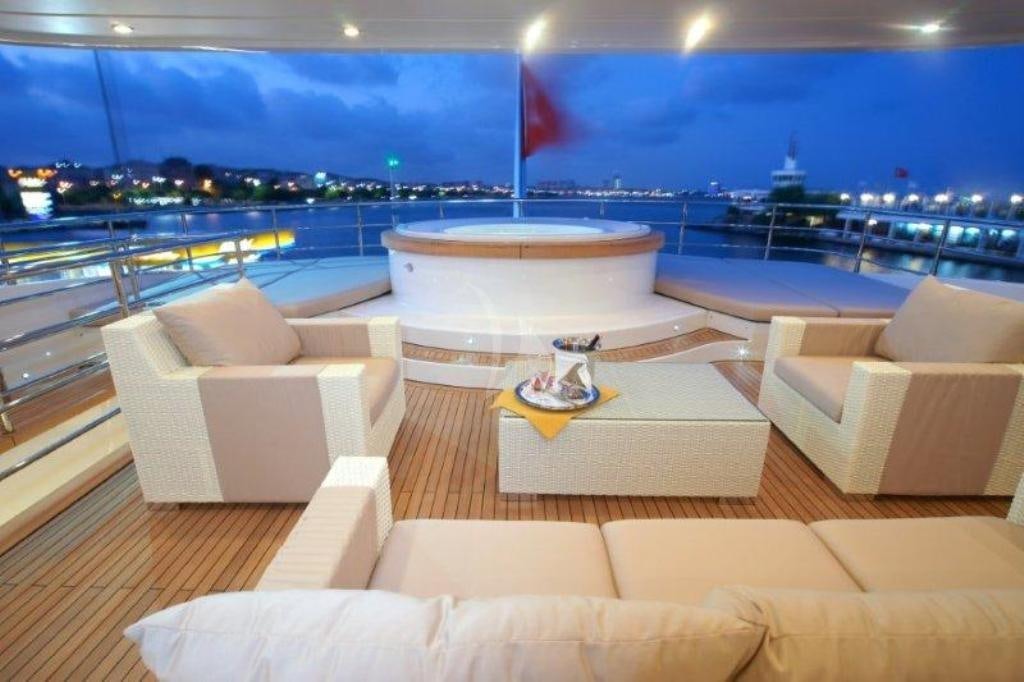 a lounge area with a view of the water and a city in the background aboard TATIANA I Yacht for Charter