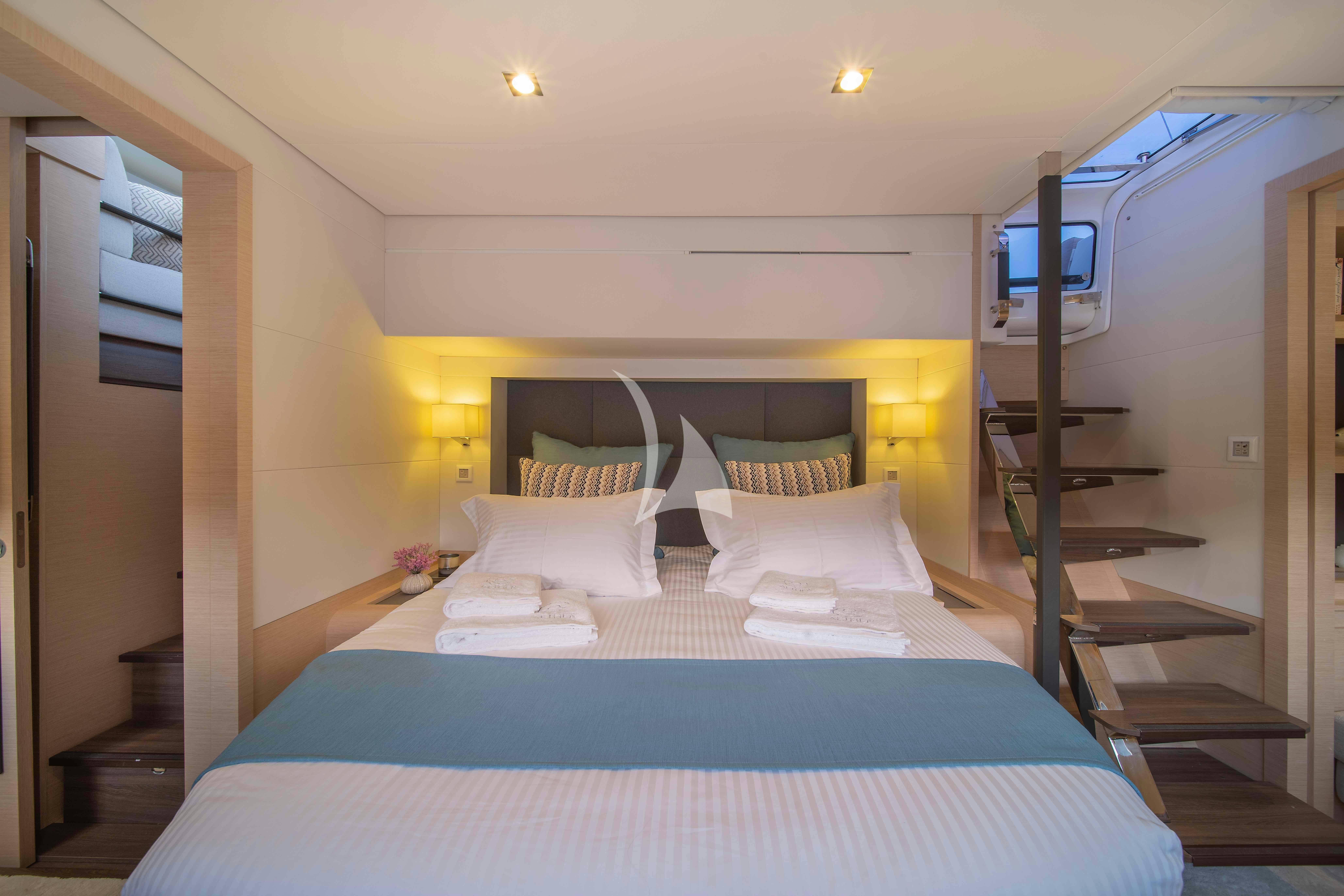 a bed with blue sheets aboard AETHER Yacht for Charter