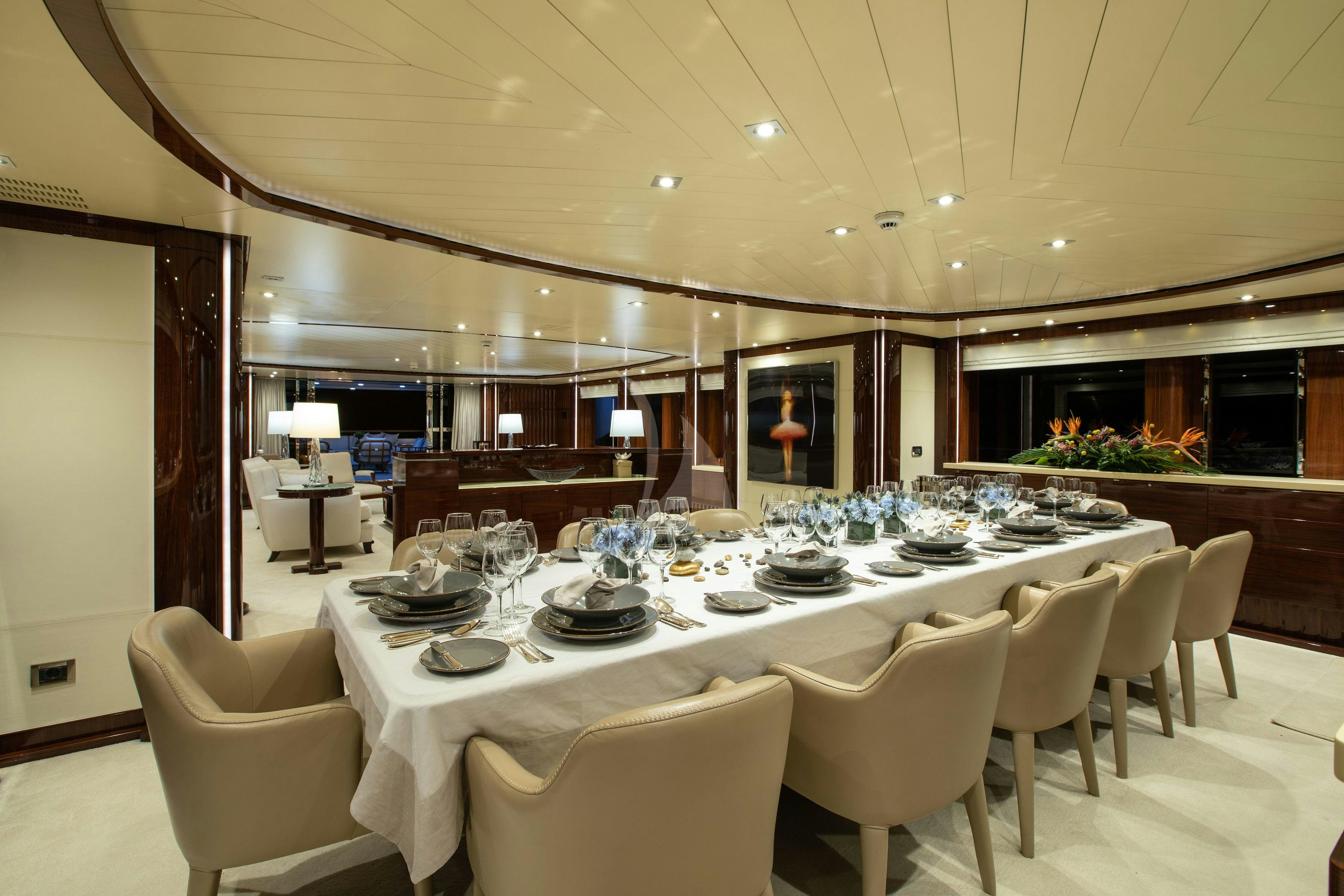 a large dining table with white chairs aboard VERTIGO Yacht for Charter