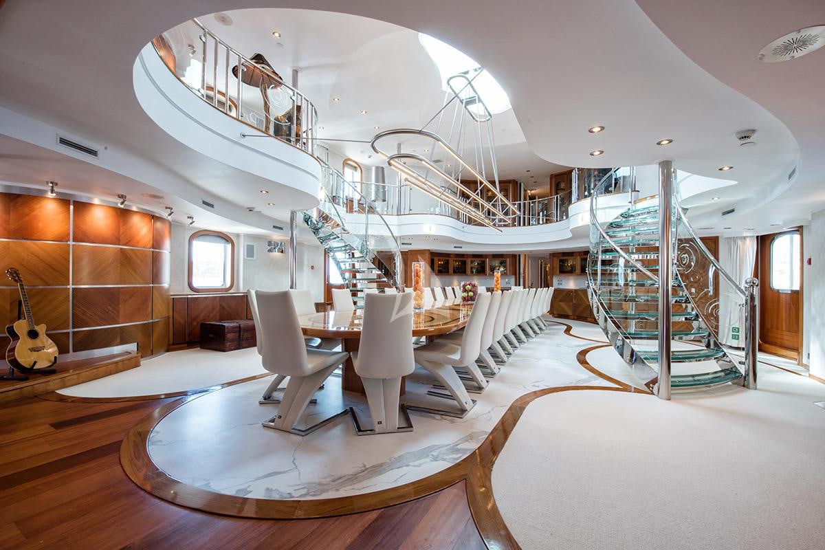 a large room with a staircase and a large white table aboard SHERAKHAN Yacht for Charter
