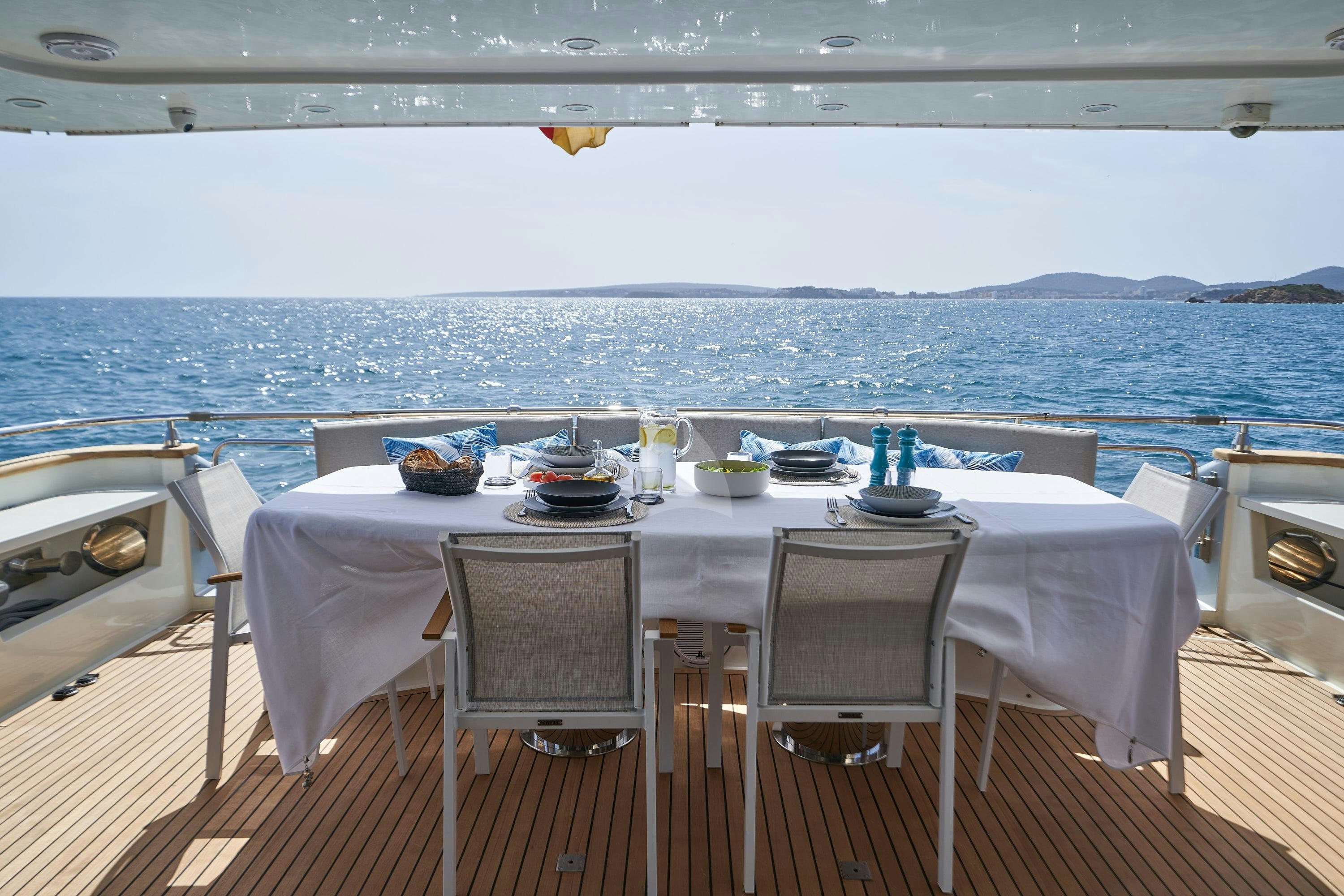 a table set for a meal on a deck overlooking the ocean aboard KIAWAH II Yacht for Charter