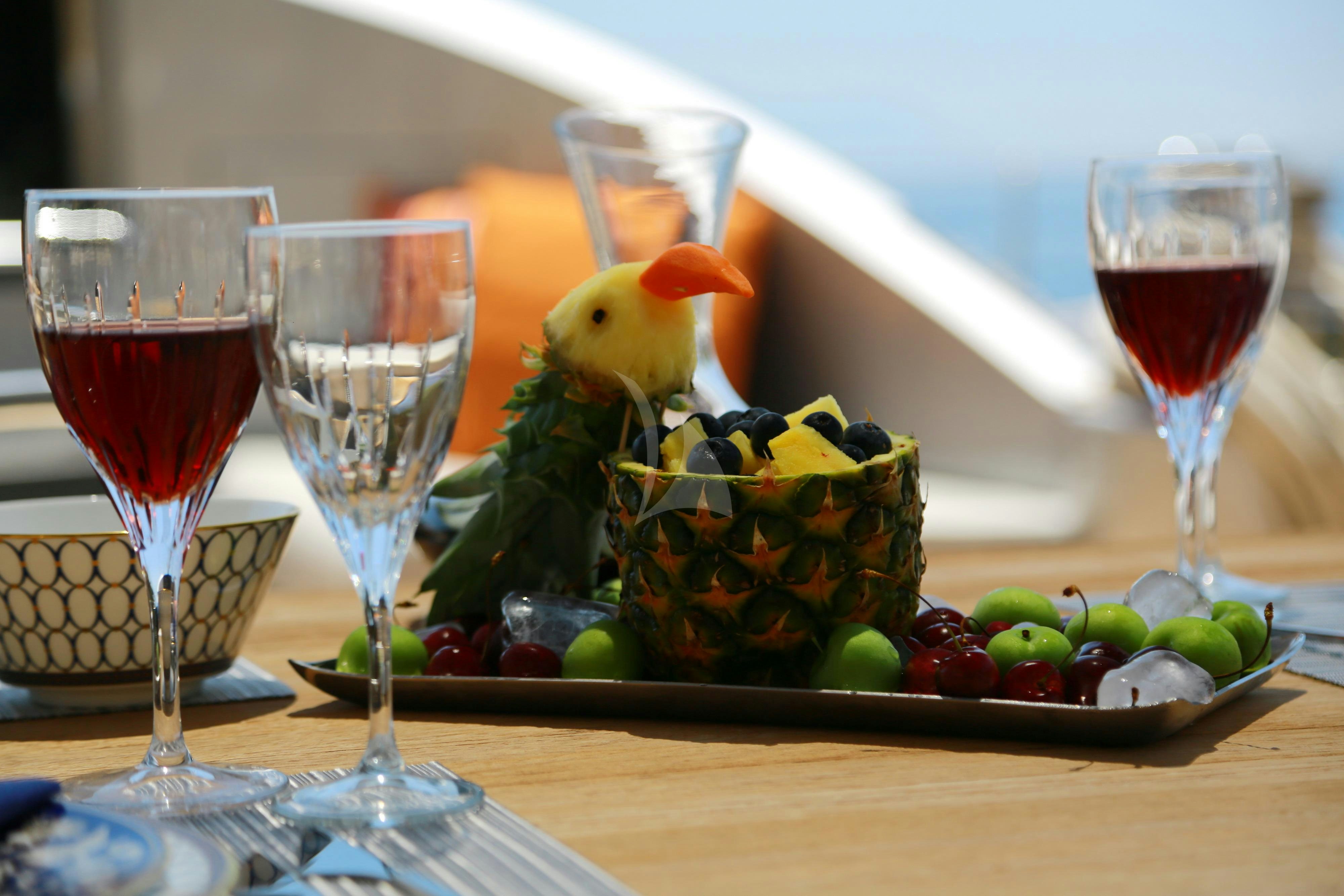 a bowl of fruit next to a glass of wine aboard MUSIC Yacht for Charter
