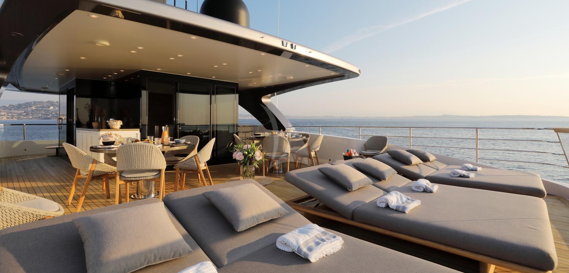 a room with a bed and a table and chairs aboard X Yacht for Charter