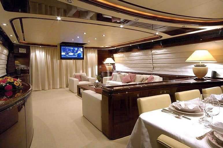 a room with a couch and a table with chairs and a television aboard TWO KAY Yacht for Charter