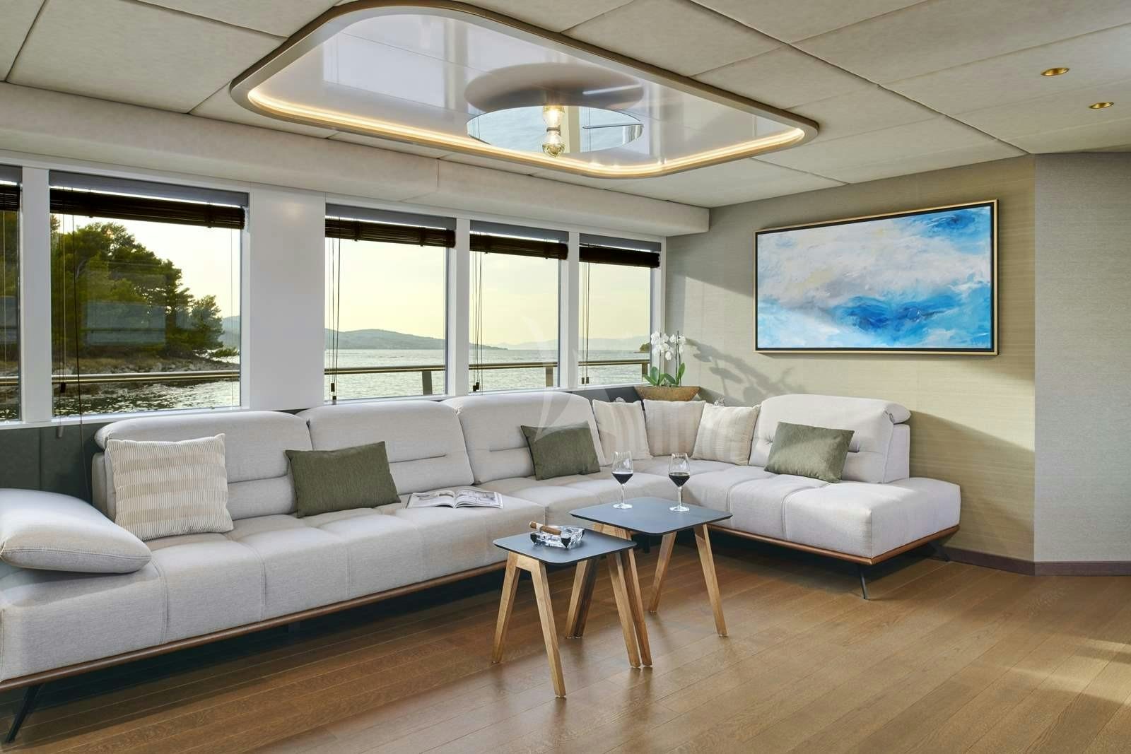 a living room with a large white couch and a large window aboard ANIMA MARIS Yacht for Charter