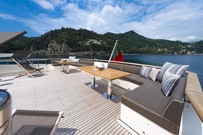 a deck with chairs and tables on it by a body of water aboard CLOUD ATLAS Yacht for Charter