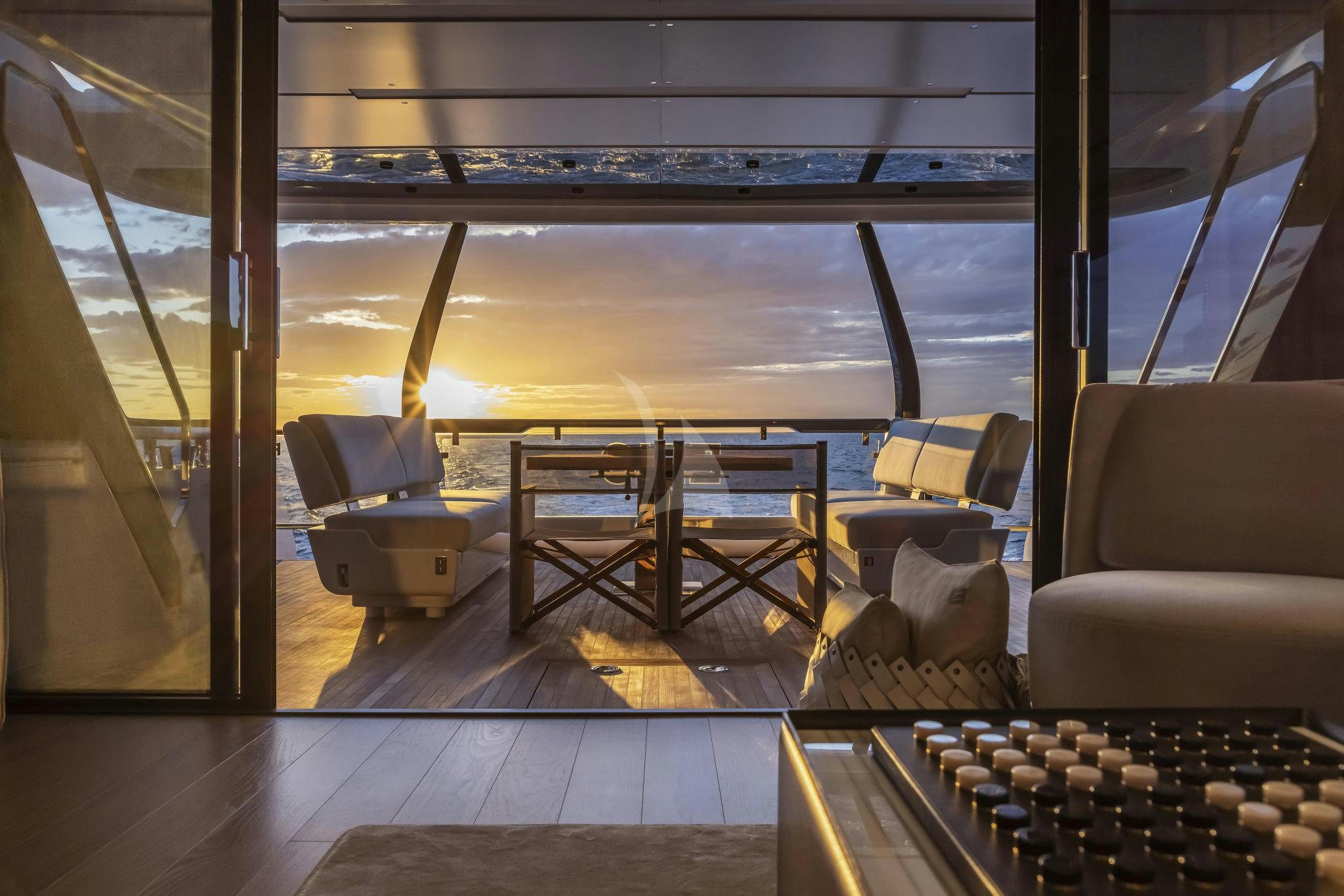 a room with a view of the water and a table aboard EPIC Yacht for Charter