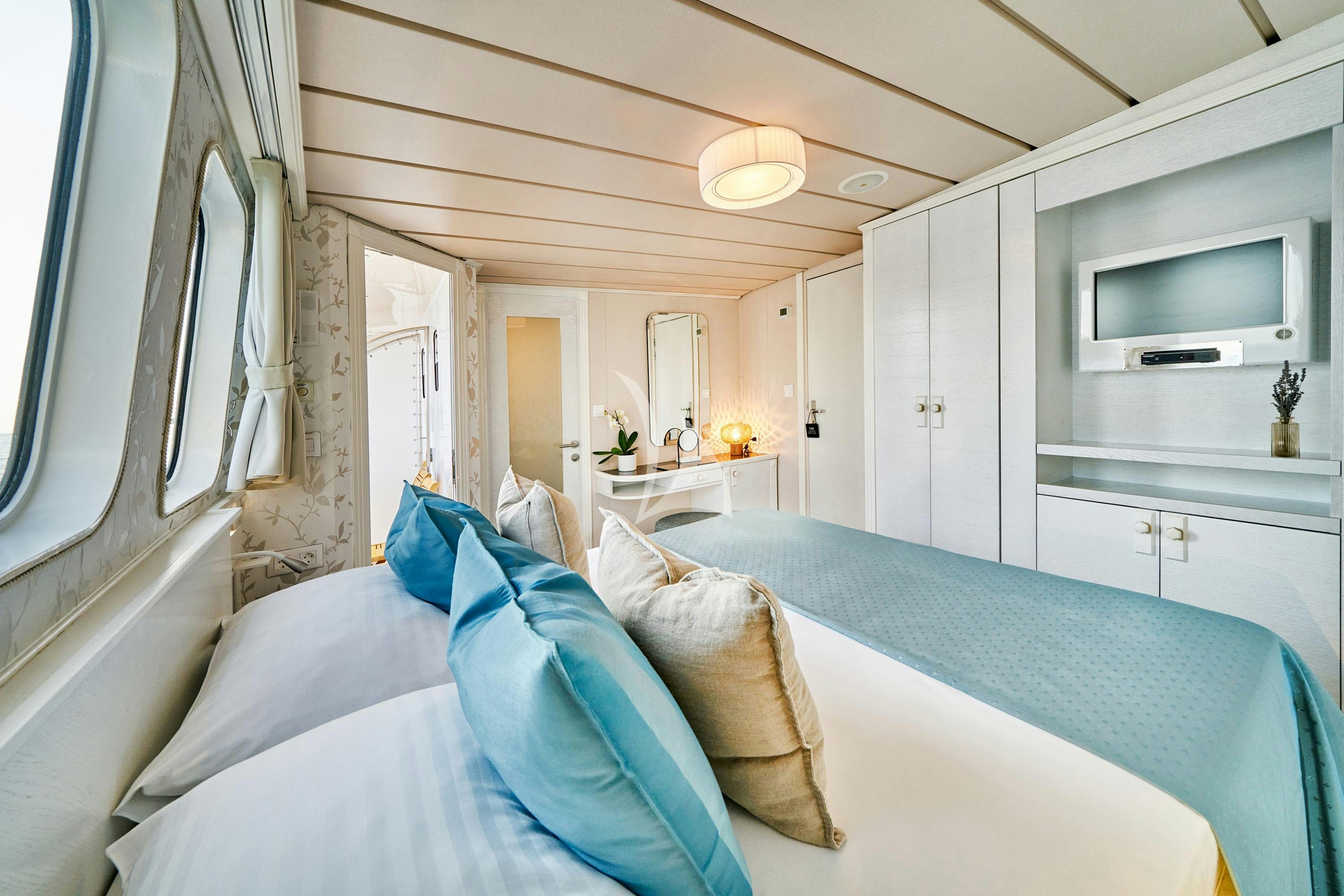 a bedroom with a bed and a television aboard LA PERLA Yacht for Charter