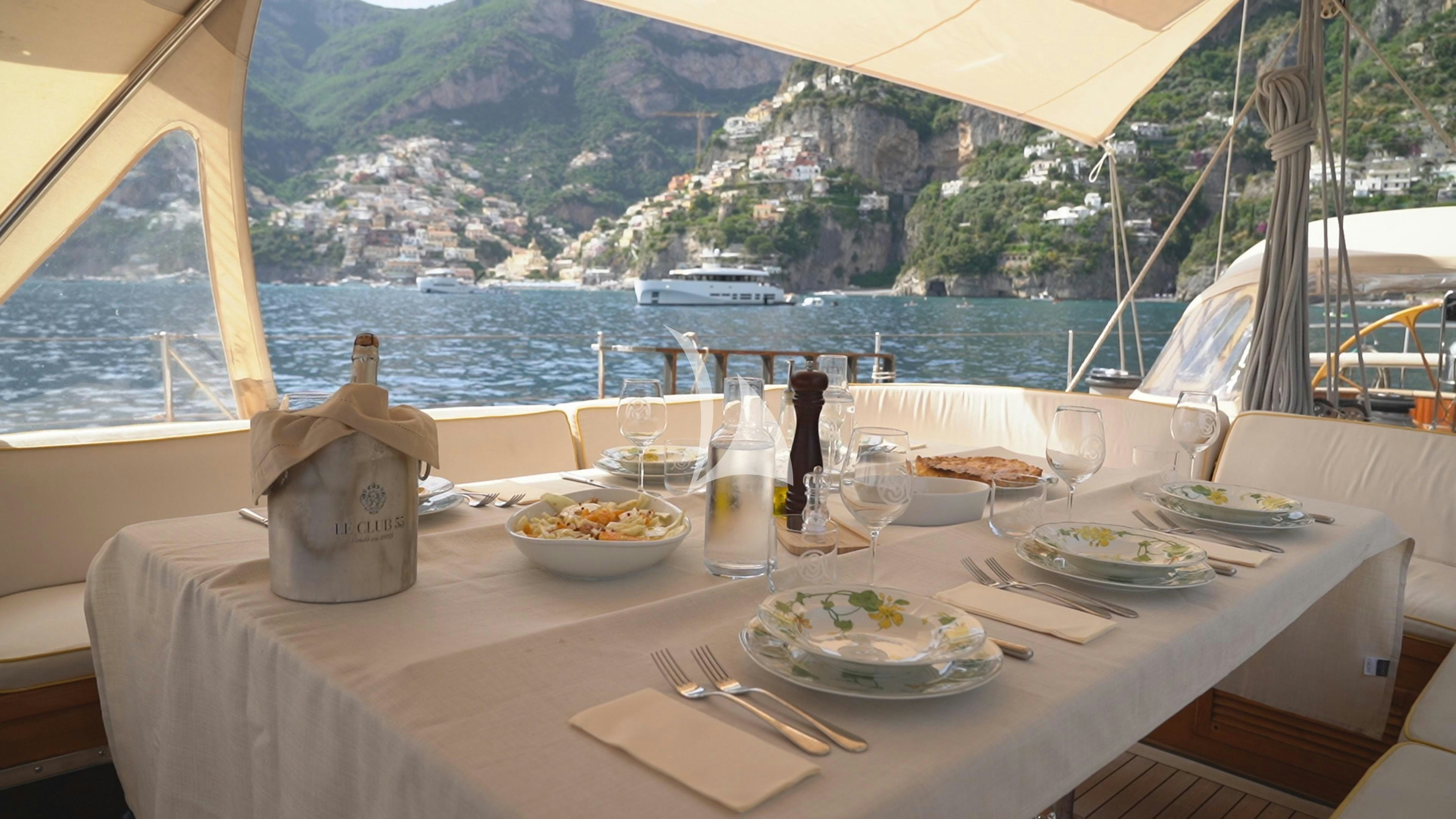 a table with plates and food on it aboard QUARTA SANTA MARIA Yacht for Sale