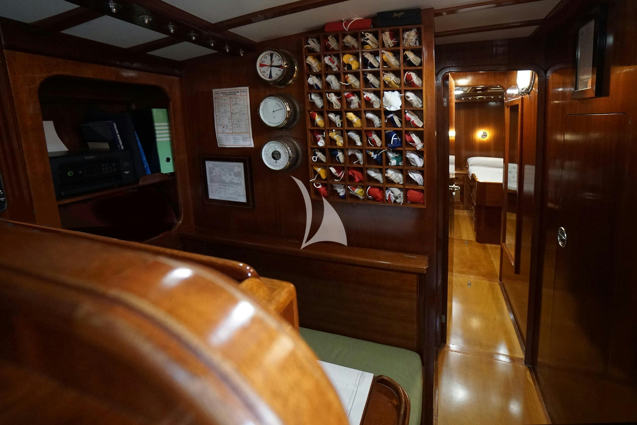 a room with a wood wall and a wood door with a wall of bottles and a clock on aboard QUARTA SANTA MARIA Yacht for Sale