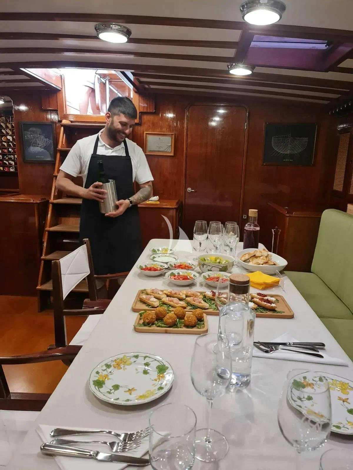a person standing at a table with food on it aboard QUARTA SANTA MARIA Yacht for Sale