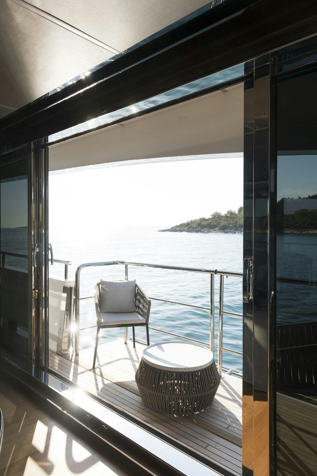a balcony with a chair and a table on the balcony aboard ANTHEYA III Yacht for Charter