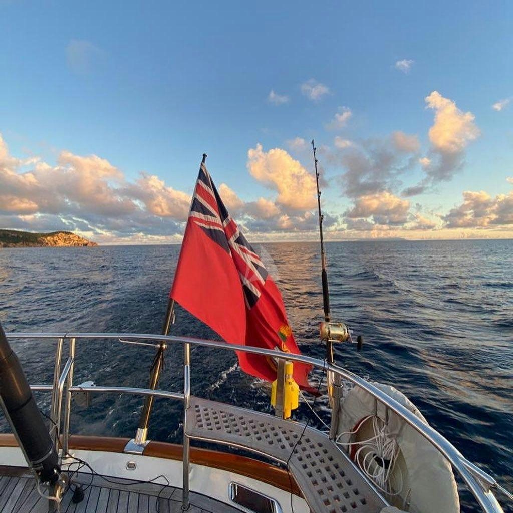 a boat with a flag on it aboard MES AMIS Yacht for Charter