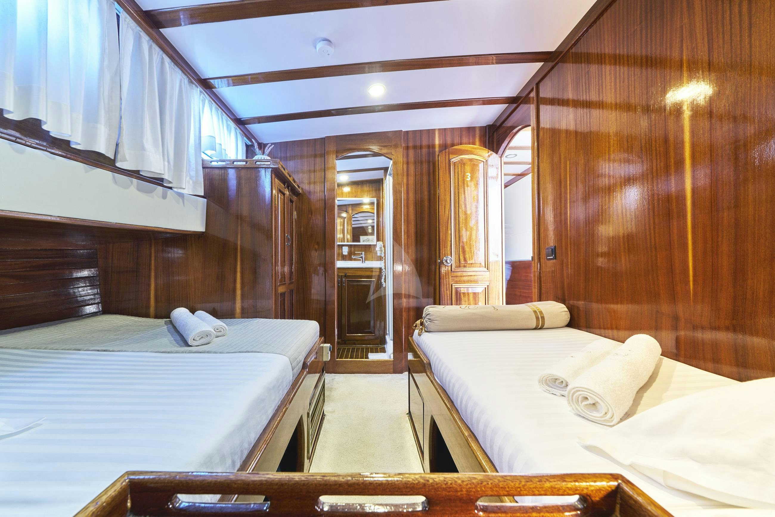 a room with beds and a door aboard PERLA Yacht for Charter