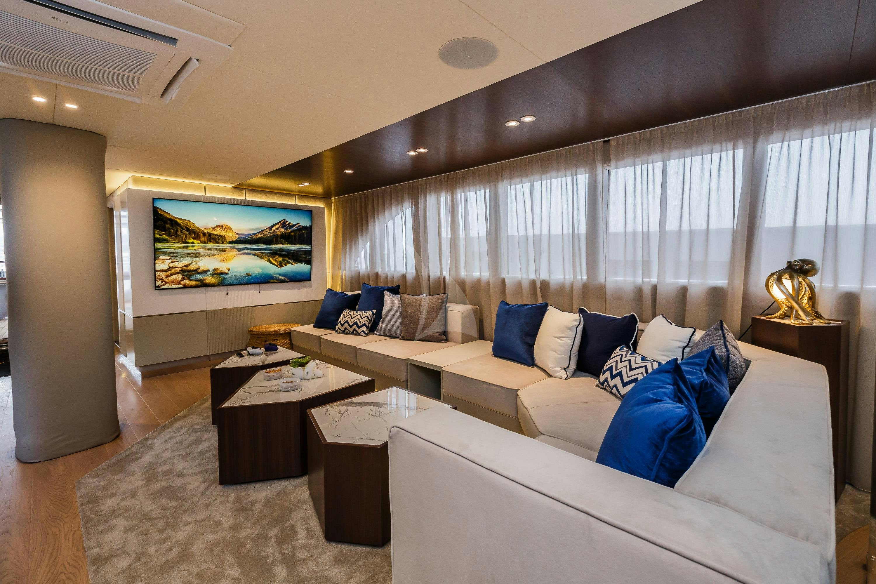 a living room with a large white couch and a large window aboard CLASE AZUL Yacht for Charter