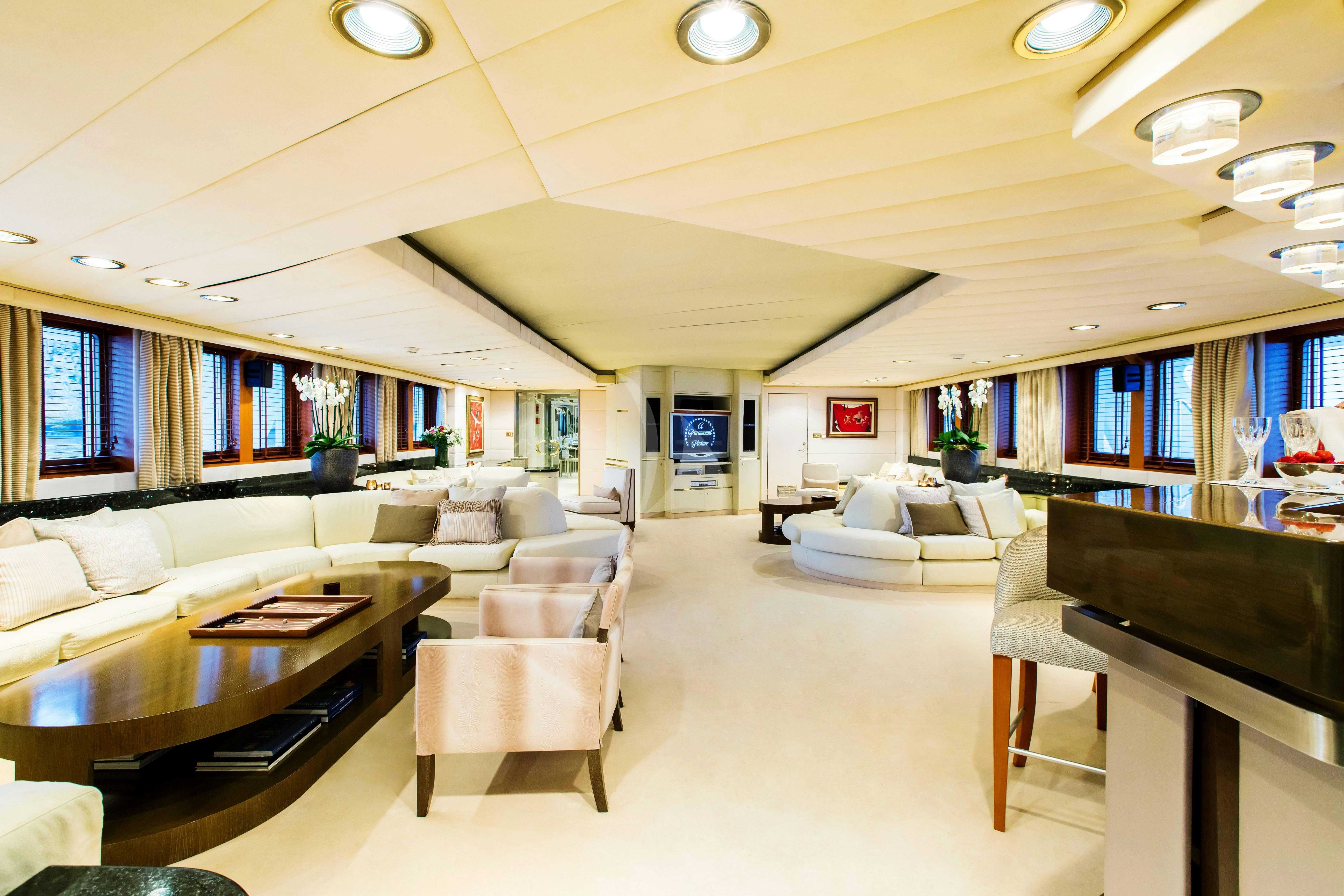a large living room with a large screen tv and a large black piano aboard ESMERALDA Yacht for Charter